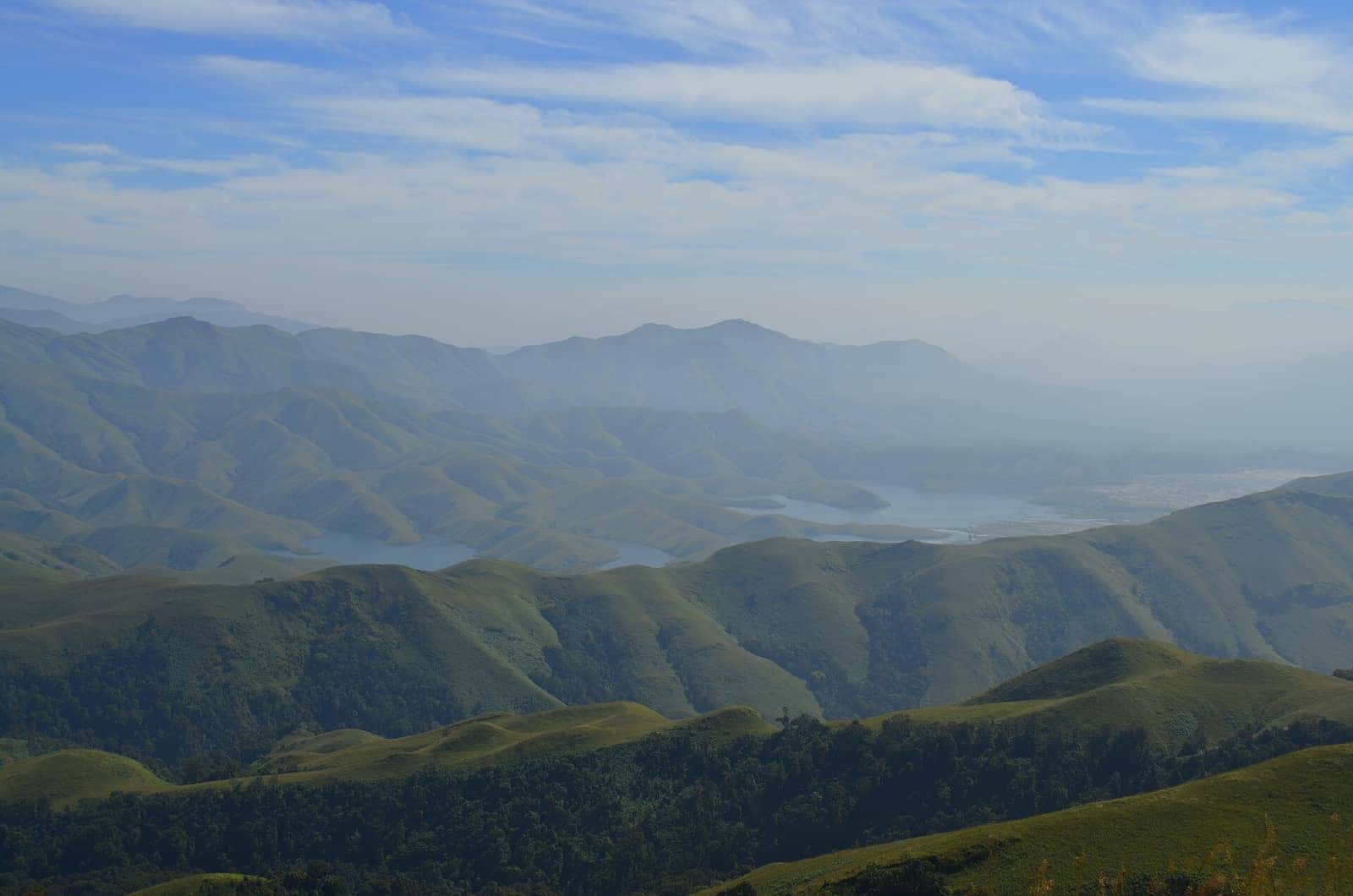 Layered green ranges and a reservoir seen from Gangalikal peak in the Kudremukh range