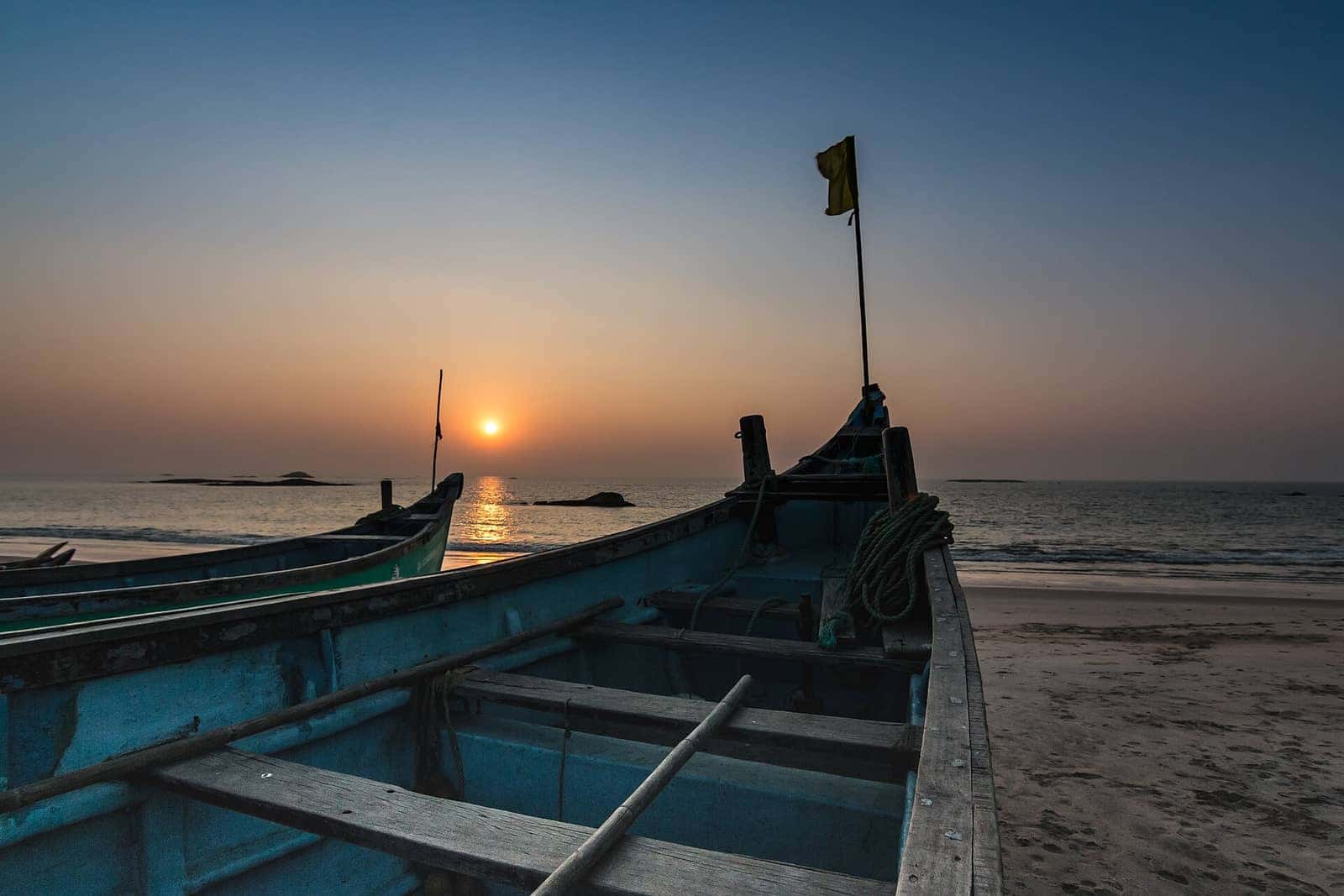 Sunset over the Arabian Sea with a fishing boat on the sand near Mangaluru