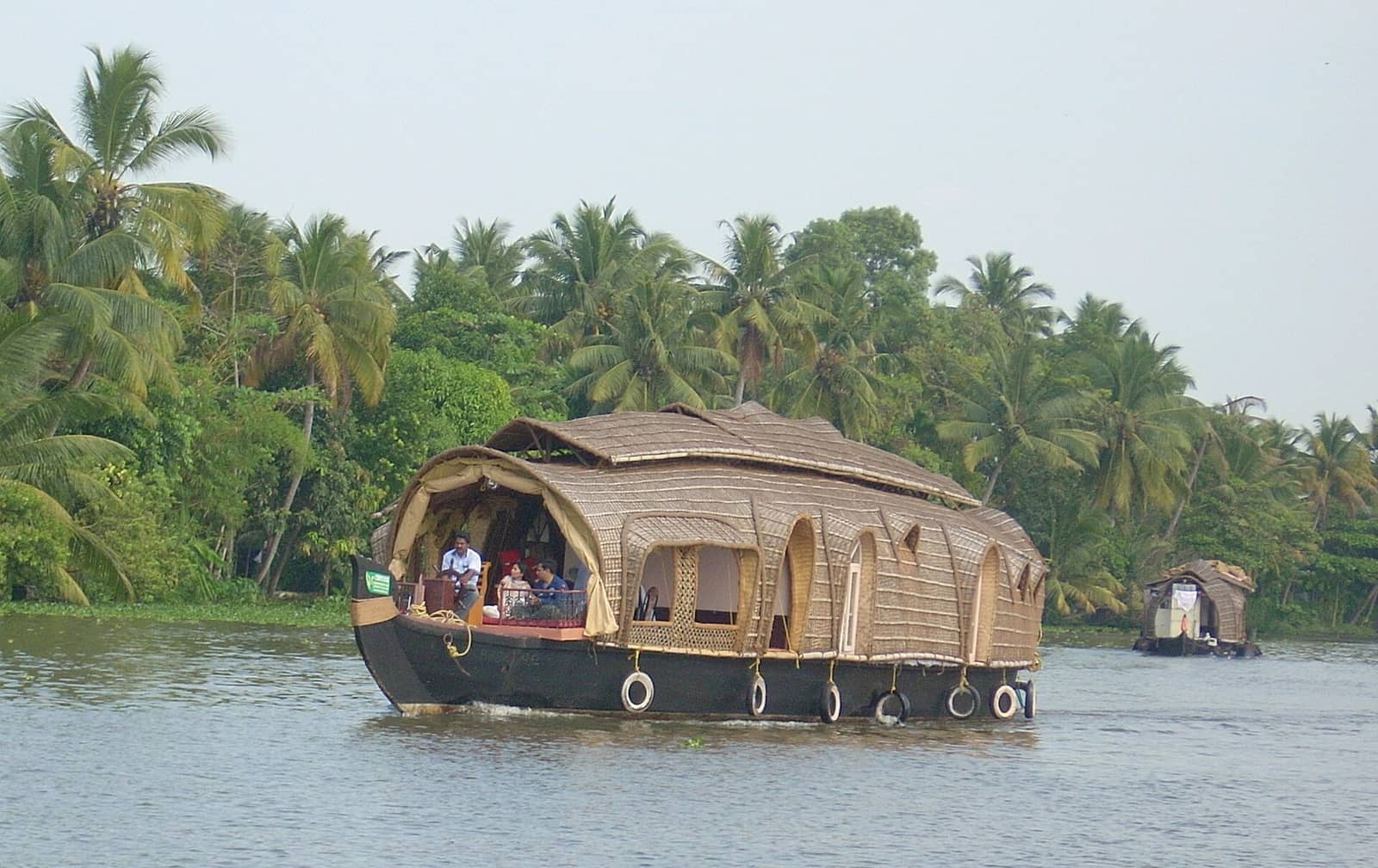 A traditional Kerala houseboat gliding past coconut palms